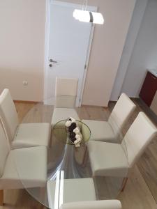 una mesa de centro de cristal con sillas blancas y una lámpara en Apartments Joja, en Međugorje