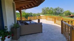 patio con mobili in vimini e terrazza in legno di Pensiunea NEST a Dunavăţu de Jos