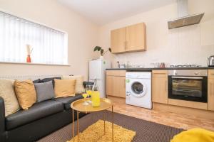 a living room with a black couch and a kitchen at Lovely 1 bed apart.Contractors.NearRussellHillHosp in Brierley Hill