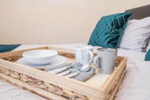 a tray with plates and cups and utensils on a bed at Lovely 1 bed apart.Contractors.NearRussellHillHosp in Brierley Hill