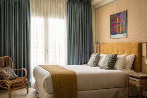 pokój hotelowy z dużym łóżkiem i krzesłem w obiekcie BYPILLOW Residence Abril w Sewilli