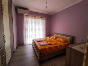 um quarto com uma cama com lençóis laranja e uma janela em Cheerful 2 bedroom villa with free parking. em Gjirokastër