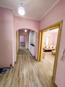 an empty living room with pink walls and wooden floors at Cheerful 2 bedroom villa with free parking. in Gjirokastër +11 photos