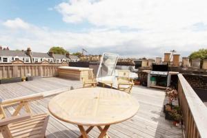 una terraza de madera con mesa y sillas en el techo en Sunny 2 bedroom, 2 bathroom Apartment with Roof Terrace, en Londres