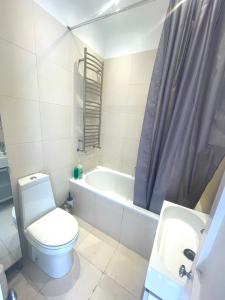 a bathroom with a toilet and a tub and a sink at Sunny 2 bedroom, 2 bathroom Apartment with Roof Terrace in London