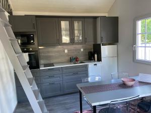 a kitchen with gray cabinets and a table and a table and chairs at VillaAttefall in Färjestaden