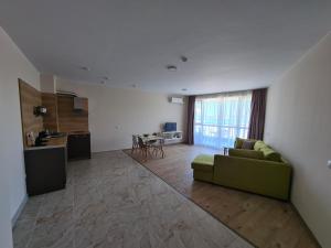a living room with a green couch and a kitchen at Aparthotel Happy in Primorsko