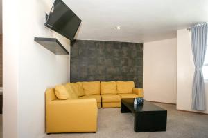 a living room with a yellow couch and a tv at Hotel Euro Confort,Pachuca in Pachuca de Soto