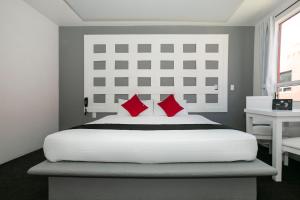 1 dormitorio con 1 cama blanca grande con almohadas rojas en Hotel Euro Confort,Pachuca, en Pachuca de Soto