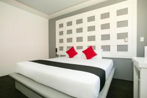 1 dormitorio blanco con 1 cama blanca grande con almohadas rojas en Hotel Euro Confort,Pachuca, en Pachuca de Soto