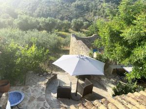 a white umbrella sitting on top of a patio at CASA LOLA Naturaleza, Montañas y Piscina Compartida De Pueblo in Carroja