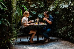 un hombre y una mujer sentados en una mesa en un jardín en Hotel Well and Come, en Barcelona