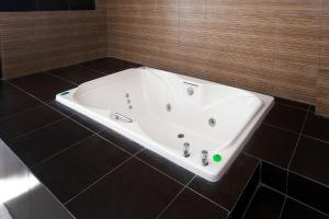 a white bath tub in a bathroom with black tiles at Hotel Euro Confort,Pachuca in Pachuca de Soto +44 photos