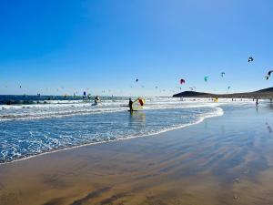 a group of people standing in the water at the beach at Surfers Lodge in El Médano