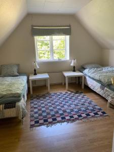 a attic room with two beds and a rug at Bondehus - Dansk bondehus med patina in Sindal