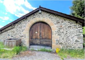 un antico edificio in pietra con una grande porta in legno di Maison chaleureuse à Bagnac-sur-Célé 70 m² avec jardin accueillant a Linac