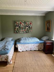 a bedroom with two beds and a painting on the wall at Bondehus - Dansk bondehus med patina in Sindal