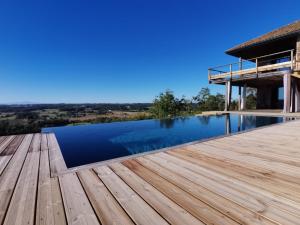 a pool with a wooden deck next to a house at Le Bivouac bivouacbyalain in Pimbo