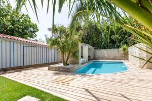 een achtertuin met een zwembad en een houten terras bij Le Chai de La Boirie in Saint-Pierre-dʼOléron