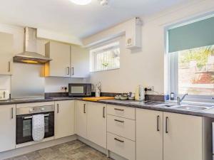 a kitchen with white cabinets and a sink and a window at Lovely Magnolia Apartment- 1king and 4 Single Accommodation Torquay in Torquay