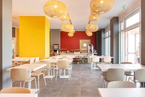 um restaurante com mesas e cadeiras brancas e paredes amarelas em B&B Hotel Roma Fiumicino Aeroporto Fiera 2 em Fiumicino