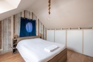 1 dormitorio con cama blanca y cortina azul en Maison de la Gaîté, en Amboise