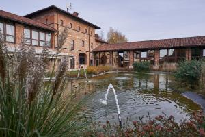 a pond in front of a brick building with a fountain at RELAIS CASCINA ERA in Sandigliano