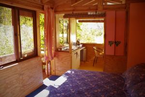 um quarto com uma cama e uma cozinha com janelas em El Jardín Secreto-Pisco Elqui em Pisco Elqui
