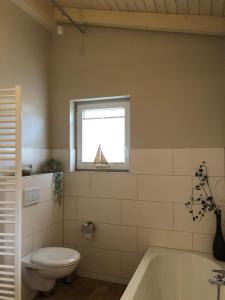 a bathroom with a tub and a toilet and a window at Ferienwohnung Mester in Osterrönfeld