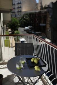 een zwarte tafel met twee glazen en peren op een balkon bij Le Centre Ville in Athene
