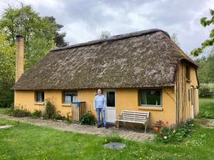 een vrouw die voor een geel huis staat bij Mor’s hus Læsø in Læsø