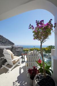 a patio with two chairs and a tree with flowers at Endless Traditional Houses in Fira