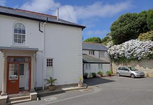 een wit huis met een auto geparkeerd op een parkeerplaats bij Mount Royal - Penzance in Penzance