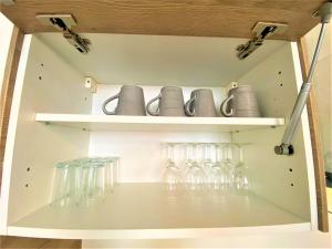 a shelf with glasses and cups on it at Appartements Rue Sarret XXL in Angers