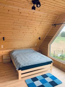 a bed in a wooden room with a window at Kamyczek in Stare Juchy