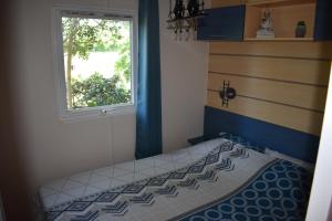 Dormitorio pequeño con cama y ventana en mobil-home sur terrain bucolique, en Hyères