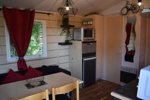 a kitchen and living room with a table and a microwave at mobil-home sur terrain bucolique in Hyères