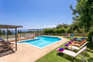 a swimming pool with chaise lounge chairs and a swimming poolvisor at Villa Olive Grove by Villa Plus in Marathi