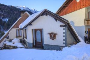 a house with snow on the ground next to a building at Il Marangon in Prato Carnico