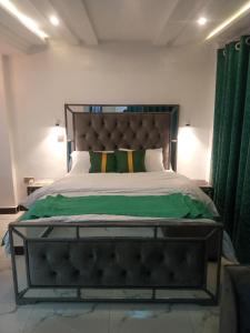 a bedroom with a large bed with green curtains at Muka homes in Naivasha