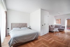 - une chambre blanche avec un lit et un canapé dans l'établissement Exclusive OldNew apartments in city center, à Panevėžys