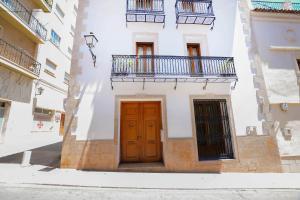 biały budynek z drewnianymi drzwiami i balkonem w obiekcie Casa Paquita w mieście Calpe