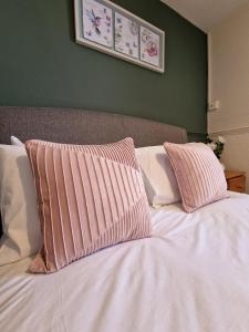 a bed with two pink and white pillows on it at The Foresters Arms in Tarporley