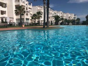 una piscina de agua azul frente a los edificios en Las terrazas de la torre golf Heidi en Murcia