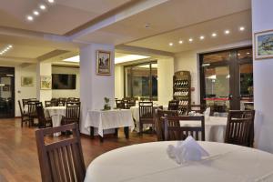 a restaurant with white tables and chairs and windows at Forest Retreat&Spa in Oveselu