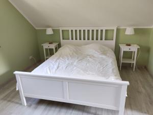 ein weißes Bett in einem Zimmer mit 2 Tischen in der Unterkunft Domek wakacyjny nad jeziorem Gowidlińskim in Podiazy