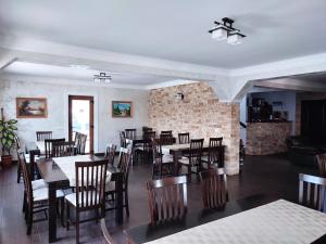 a restaurant with tables and chairs and a brick wall at Pensiunea Sub Horiță in Leordina