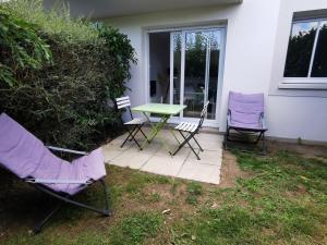 eine Terrasse mit 2 Stühlen, einem grünen Tisch und Stühlen in der Unterkunft Appartement proche plages in Brancieux