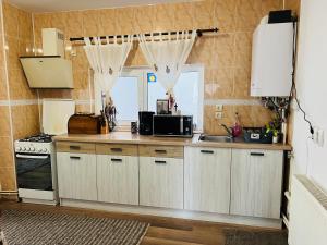 uma cozinha com armários brancos, um lavatório e um micro-ondas em Casa Bunicii Sinaia em Sinaia