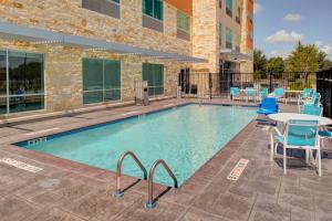 a swimming pool with a table and chairs and a building at Holiday Inn Express & Suites - Houston NW - Cypress Grand Pky, an IHG Hotel in Cypress